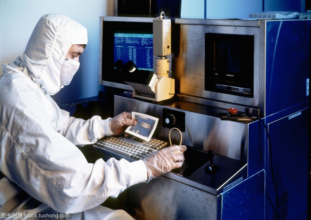 模型發(fā)布。硅晶片檢查。一名技術(shù)人員拿著一張硅片的部分照片,同時對其微電路進行檢查。他坐在顯微鏡下觀察晶圓的放大。這是一個&ldquo;干凈的房間&rdquo;,技術(shù)人員穿著一套身衣,兜帽和面罩。在所有過程涉及人工微電路的制作和測試技術(shù)人員穿防護服和手套空氣潔凈室的過濾。即使是最小的塵埃微粒也可能破壞其中的一個微電路。